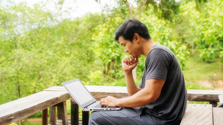 Asian man using a laptop on the balcony.の写真素材