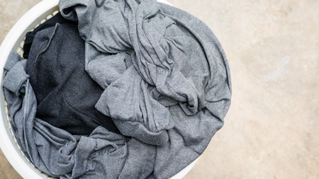 Gray clothes in a white hamper on a cement background.の写真素材