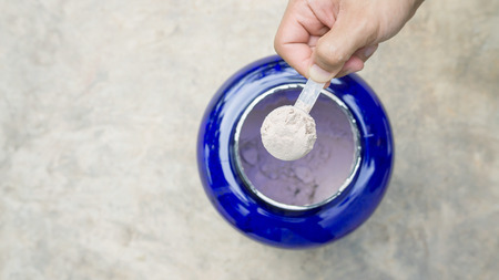 Man holding a whey protein on gray background.の写真素材
