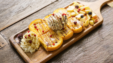 Honey Toast and ice cream with mixed fruit on a wooden table.の写真素材