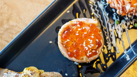 Fresh salmon eggs sushi on a black plate (Japanese food).の写真素材
