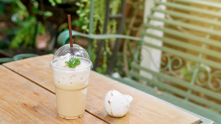 Coffee smoothie on a wooden table and plant background.の写真素材
