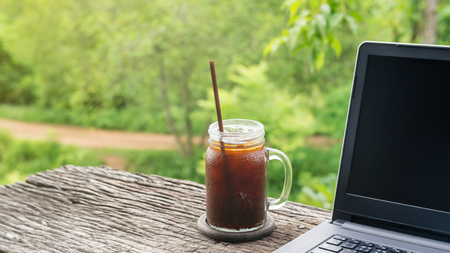 Iced americano coffee and laptop on a wooden table.の写真素材
