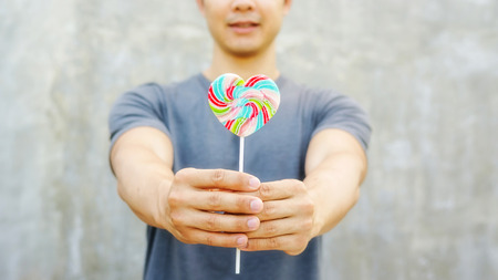 Man holding a lollipop on a gray .の写真素材