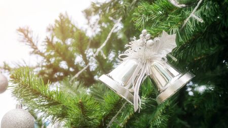 Silver bells hanging on a Christmas tree.