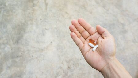 Man holding a pill on a gray background.の写真素材