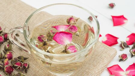A cup of tea pink rose on a white wooden table.の写真素材