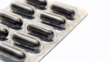 Black pill capsule on a white background, selective focus.の写真素材