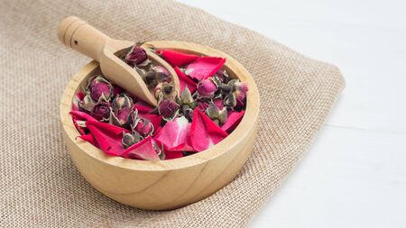 A dry tea pink rose on a white wooden table.の写真素材