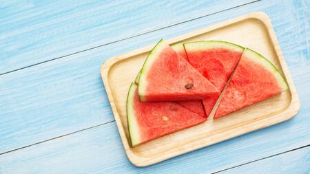 Red watermelon on a plate and blue wooden table.の写真素材
