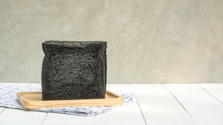 Black charcoal bread on a white wooden table.の写真素材