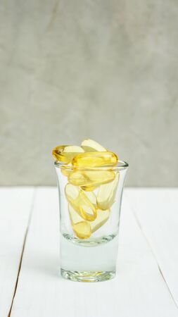 Fish oil in a glass on a white wooden table.の写真素材
