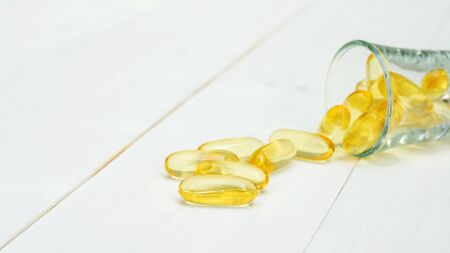 Fish oil in a glass on a white wooden table.の写真素材