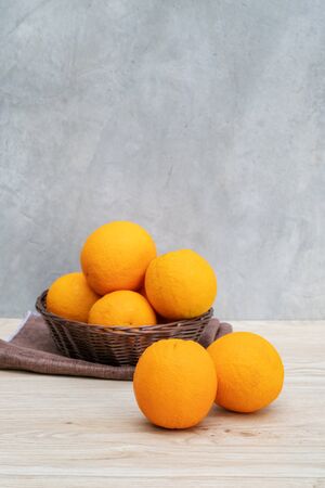 Oranges fruit in a basket on a wooden table.の写真素材