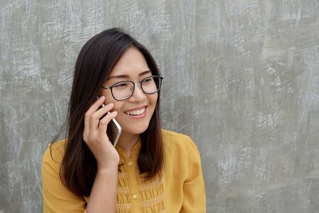 Asian woman wears a glasses and using a smartphone on  grayの写真素材