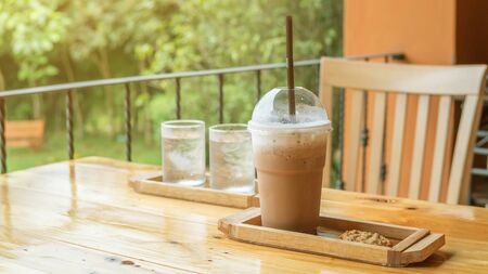 Iced coffee, cookie, and drinking water on a wooden table.の写真素材