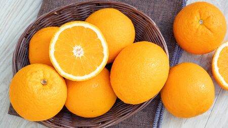 Oranges fruit in a basket on a wooden table.の写真素材