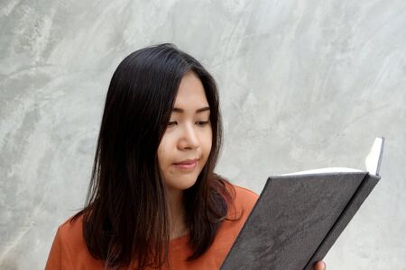 Asian woman reading a book on  gray