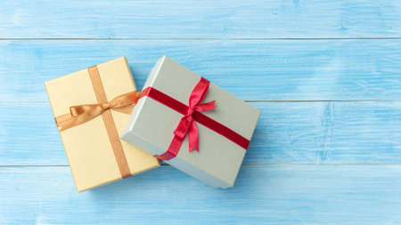 Silver and gold gift box on a blue wooden table.の写真素材