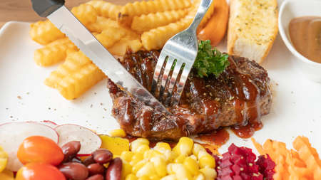 Beefsteak, French fries, and vegetable on a white plate.の写真素材
