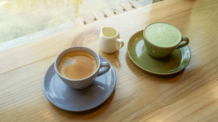A cup of hot coffee and hot green tea on a wooden table in a morning.の写真素材