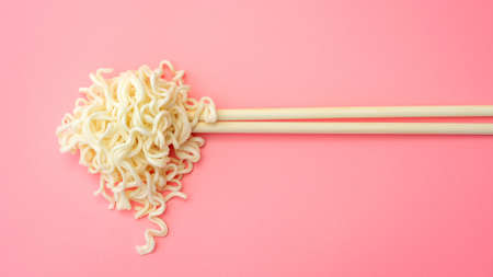 Instant noodles and chopsticks on a pink background.の写真素材