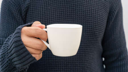 Man holding a white cup of coffee.の写真素材