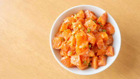 Fresh spicy salmon and rice on a wooden table.