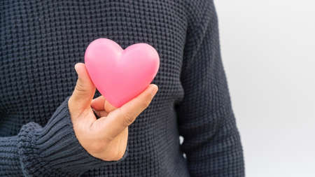 Man holding a pink heart on a white background.の写真素材