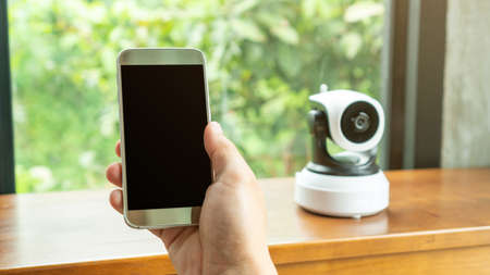 Smartphone connecting with security IP camera on a wooden table.の写真素材