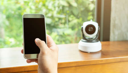 Smartphone connecting with security IP camera on a wooden table.の写真素材