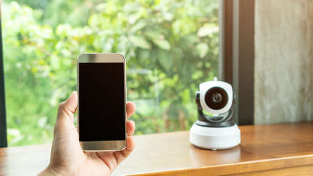 Smartphone connecting with security IP camera on a wooden table.の写真素材