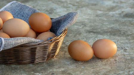 Chicken eggs in a basket on a gray background.