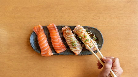 chopsticks tong fresh salmon sushi on a wooden table.の写真素材