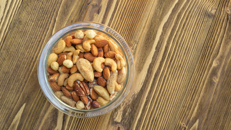 Baked mixed nuts in a bowl on a wooden background.の写真素材