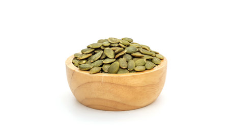 Green pumpkin seeds in a bowl on a white background.の写真素材