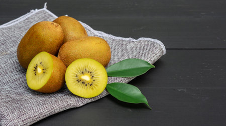 Golden kiwi on a black wooden table.の写真素材