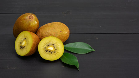Golden kiwi on a black wooden table.の写真素材