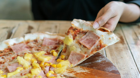 Hands taking slices of homemade Italian pizza on a wooden table.の写真素材