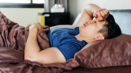 Asian young man lying on a brown bed.の写真素材