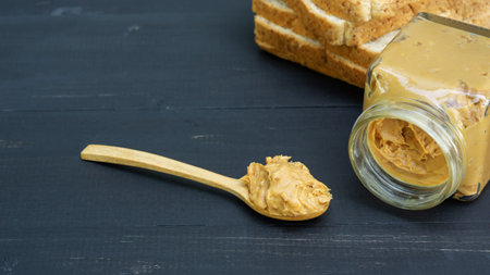 Peanut butter and whole wheat bread on a black wooden table.の写真素材