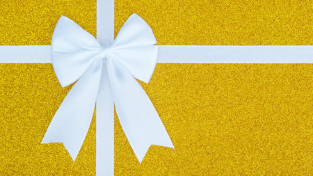 White bow and ribbon on a gold glitter gift box.の写真素材