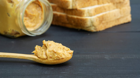 Peanut butter and whole wheat bread on a black wooden table.の写真素材