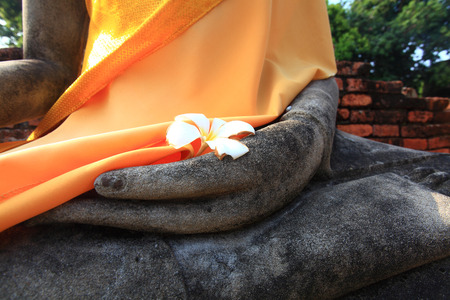 Stone hand of Buddha statue wrapped in orange curtain in Ayutthaya, Thailand.の写真素材
