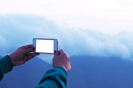 woman hand holding smartphone for take photo on top mountain at morning. subject is blurred and low keyの写真素材