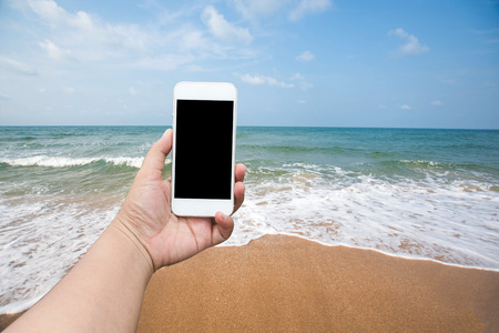 hand holding smartphone take photo seascape. soft focusの写真素材