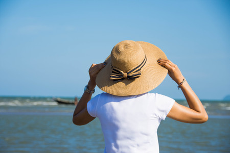 woman wear hat stand on the beach with blue sky at sunny day. soft focusの写真素材