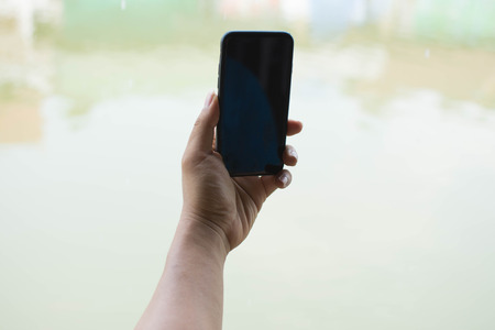 man touch screen smart phone and nature background. subject is blurred.の写真素材