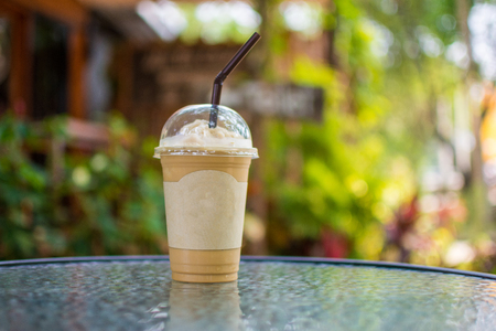 ice coffee frappe on glass table with nature background. subject is blurred.の写真素材