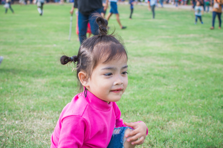 happy little girl sitting on green grass and playing in the park. soft focus.の写真素材
